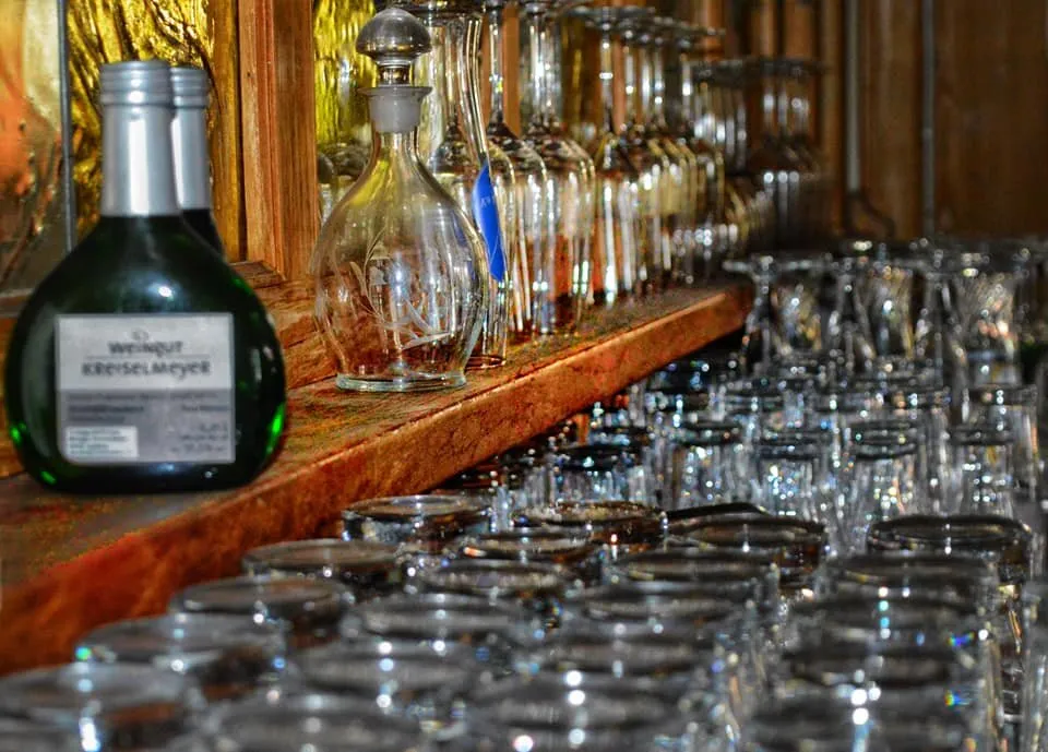 Weinregal mit Flaschen vom Weingut Kreiselmeyer und Weingläsern