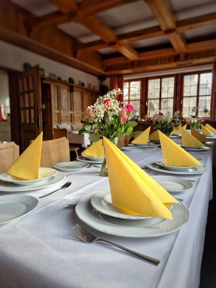 Festlich gedeckte Tafel mit gelben Servietten und Rosengesteck